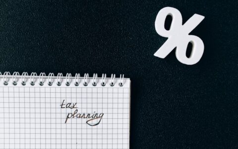 A notebook with 'tax planning' written on a grid paper next to a percent symbol on a black background.