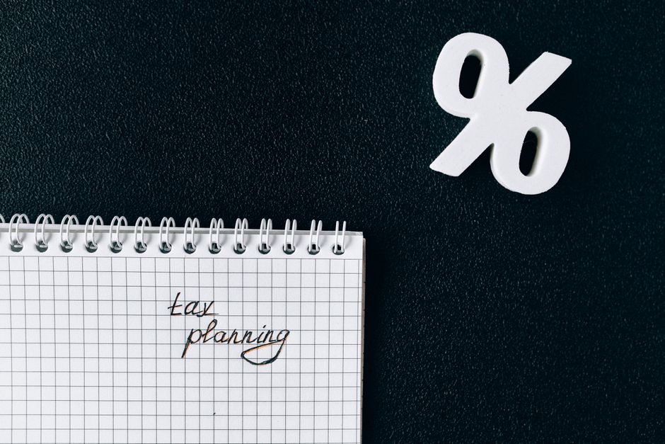 A notebook with 'tax planning' written on a grid paper next to a percent symbol on a black background.