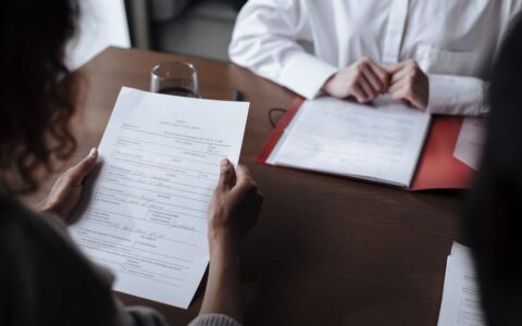 Two individuals discussing documents during a business meeting indoors.