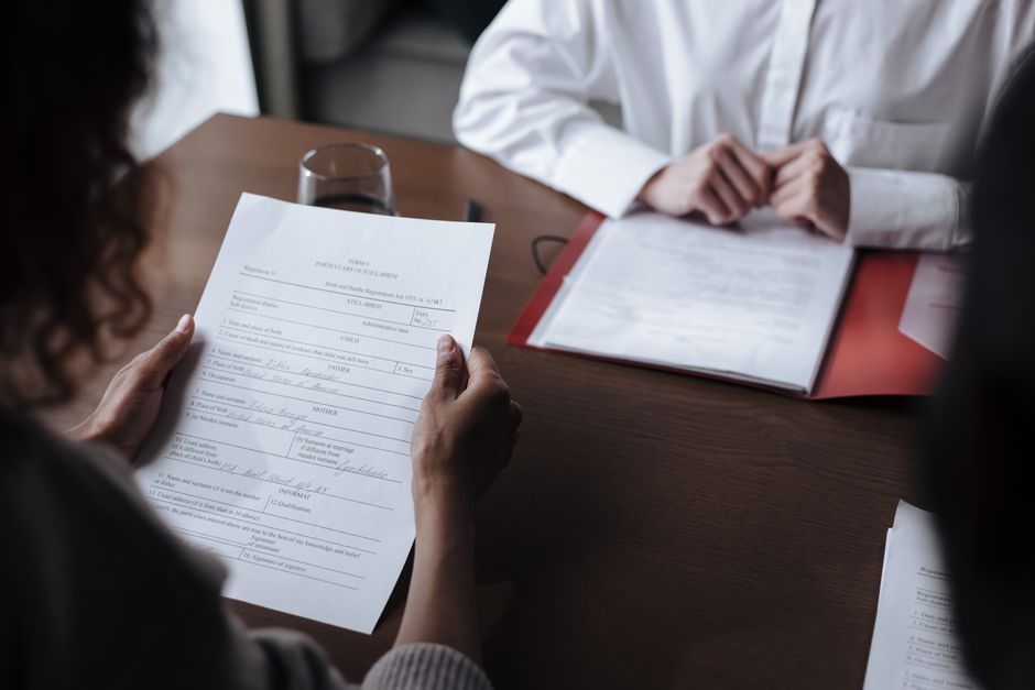 Two individuals discussing documents during a business meeting indoors.