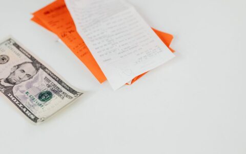 A five dollar bill and receipts on a white surface, emphasizing finance and expenses.
