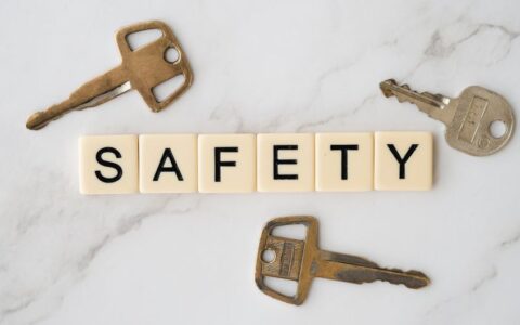 Close-up image of keys and scrabble tiles spelling 'safety' on a marble surface.