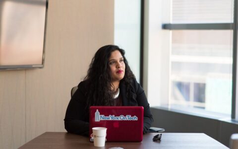 Confident woman using a laptop in a contemporary office space, focusing on her work.