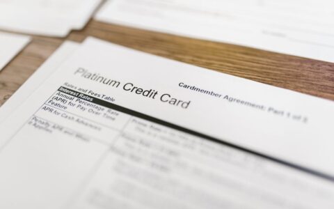 Close-up of a platinum credit card agreement document on a wooden desk.